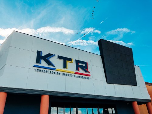 Exterior of KTR Indoor Action Sports Playground with a blue sky and clouds in the background.