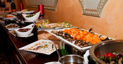 A buffet table featuring a variety of dishes, including seafood, salads, and garnishes, elegantly arranged.
