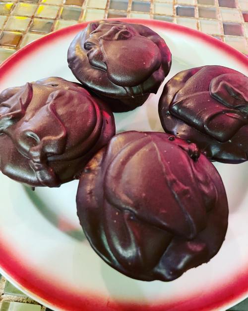 Four chocolate-covered cupcakes arranged on a red and white plate, featuring swirled frosting designs.