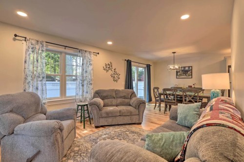 Cozy living room with gray sofas, a dining area, and large windows letting in natural light.