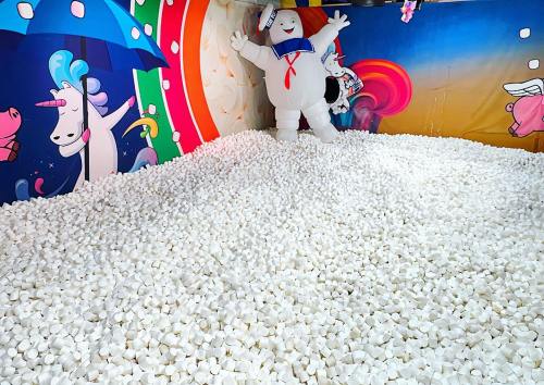 A colorful room filled with white marshmallows and a large Stay Puft Marshmallow Man figure in the background.