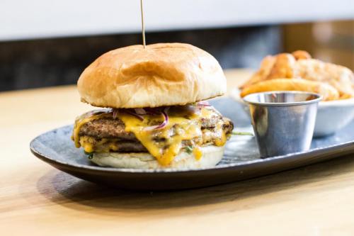 A juicy cheeseburger with two patties, melted cheese, and onions, served on a plate with a side of crispy fries.