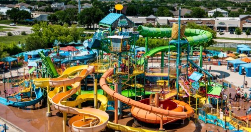 Aerial view of a colorful water park with multiple slides, pools, and visitors enjoying the attractions.