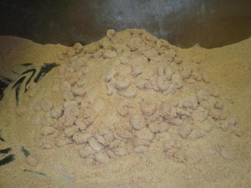 A mound of light brown, granular material resembling sand or flour, with small clumps visible on the surface.