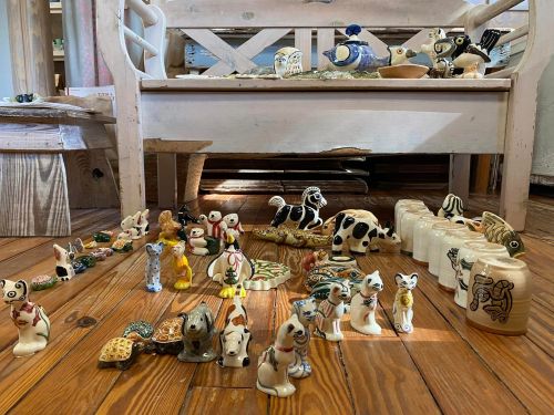 A collection of colorful ceramic animal figurines arranged on a wooden floor near a bench.