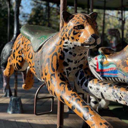A painted carousel horse designed to look like a leopard, featuring vibrant colors and intricate details.
