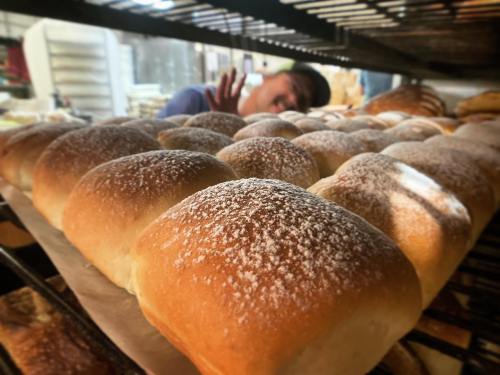 Freshly baked bread rolls dusted with flour, with a baker playfully waving in the background.