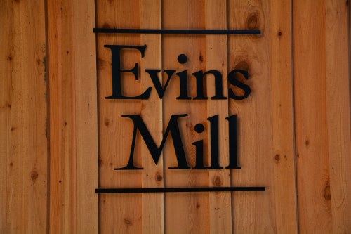 Sign reading "Evins Mill" mounted on a wooden wall.
