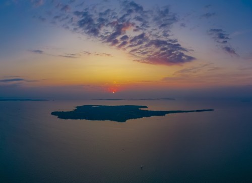 A serene sunset over a calm sea, with an island silhouette against a colorful sky.