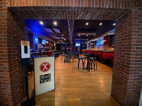 View of a bar interior with wooden floors, brick walls, and seating areas, featuring a sign for "The Rail Yard."