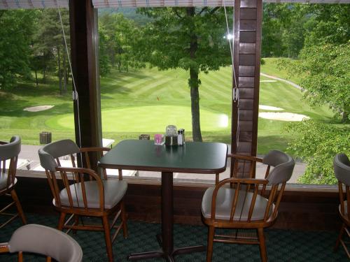 A view of a golf course from a window, featuring a table and chairs in a cozy indoor setting.