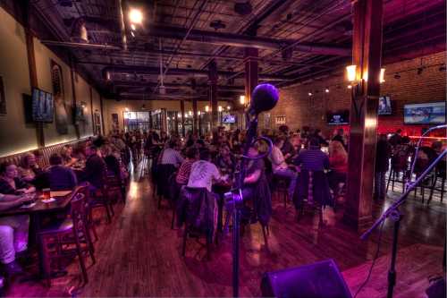 A lively bar scene with a crowd enjoying drinks and entertainment, featuring a microphone in the foreground.