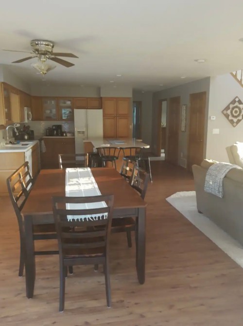 A spacious kitchen and dining area with a wooden table, chairs, and modern appliances, featuring warm lighting and decor.
