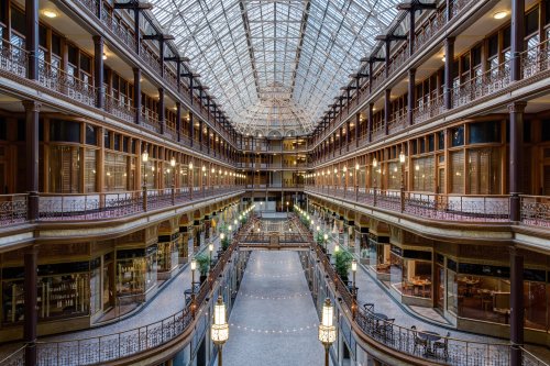 A grand indoor atrium with glass ceiling, surrounded by ornate balconies and elegant lighting.