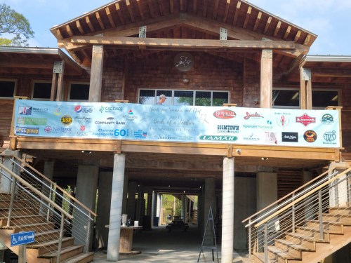 A wooden building with a large banner displaying various sponsor logos and event details above the entrance.
