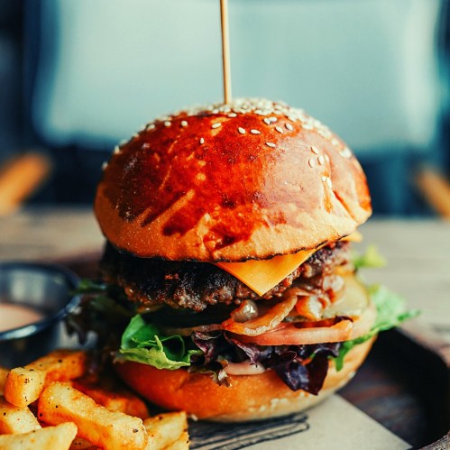 A juicy burger with cheese, lettuce, and onions, served with crispy fries on the side.