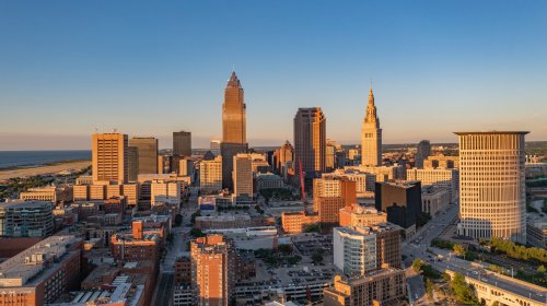 Aerial view of downtown Cleveland, Ohio, showcasing skyscrapers and the waterfront at sunset.