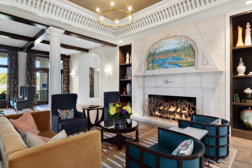 Cozy living room with a fireplace, colorful decor, and comfortable seating, featuring a scenic mural above the mantel.