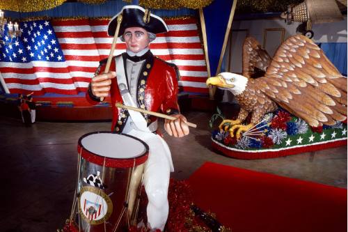 A patriotic statue of a drummer in a Revolutionary War uniform, with an eagle sculpture and American flag backdrop.