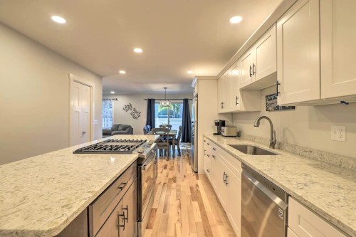 Modern kitchen with white cabinets, granite countertops, and stainless steel appliances, leading to a dining area.