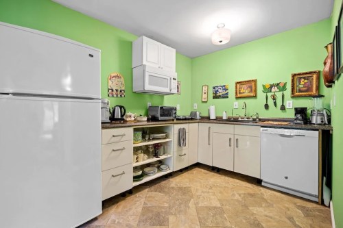 Bright green kitchen with white appliances, modern cabinets, and decorative wall art.