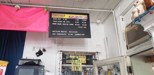 Menu board at Mayfield Ice Cream, listing prices for kids' dips, cake cones, and bottled water.