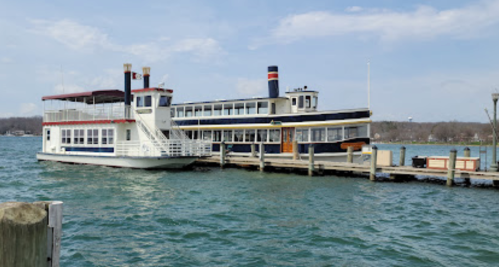 Two boats docked at a pier on a lake, with a clear blue sky and gentle waves in the water.