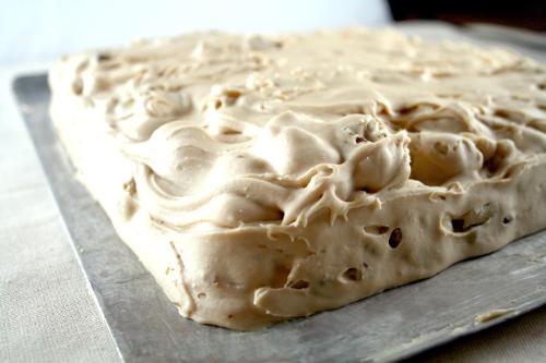A close-up of a creamy, swirled dessert on a metal tray, showcasing a smooth, light brown frosting.