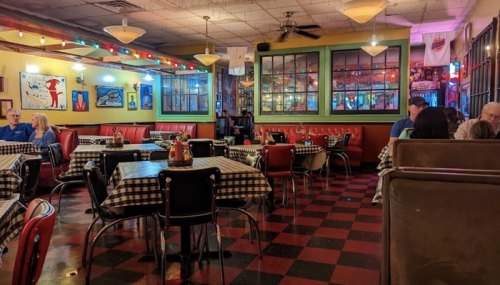 A cozy diner with checkered tablecloths, colorful decor, and patrons seated at tables, creating a warm atmosphere.