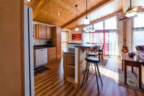 Bright, open kitchen with wooden beams, bar seating, and large windows overlooking a sunny living area.