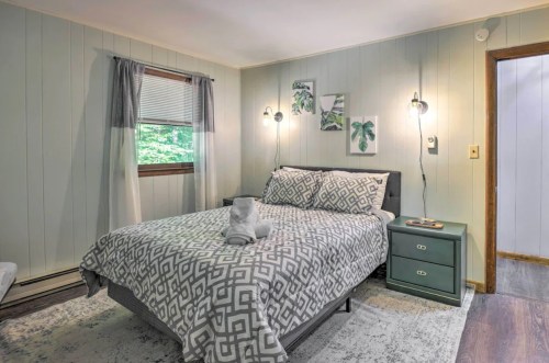 Cozy bedroom with a patterned bedspread, green nightstand, and natural light from a window.
