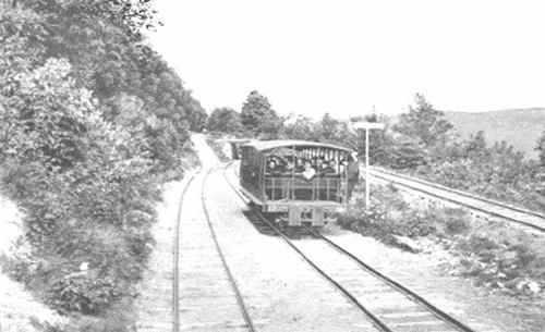 A vintage train on a curved track surrounded by trees and hills, evoking a nostalgic railway scene.