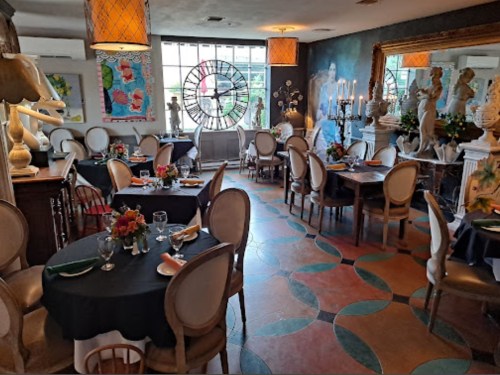 Elegant restaurant interior with tables set for dining, decorative sculptures, and colorful artwork on the walls.