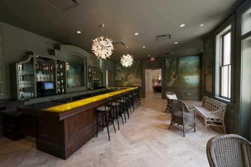 A stylish bar area with a yellow-lit counter, modern lighting, and artistic wall murals in a cozy setting.