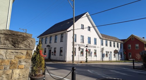 A white building with "Harmony Museum" signage, decorated for the holidays, under a clear blue sky.