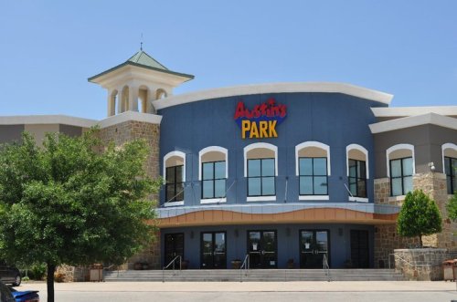 Exterior of Austin's Park, featuring a blue facade, large windows, and a tower, set against a clear blue sky.