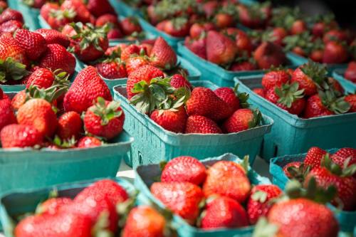 Baskets of fresh, ripe strawberries arranged neatly, showcasing their vibrant red color and green leaves.