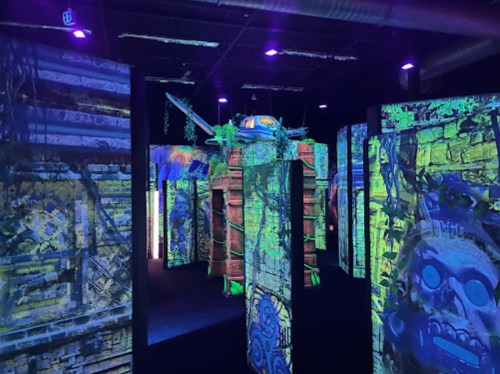A vibrant, immersive space with illuminated walls featuring colorful projections and intricate designs.