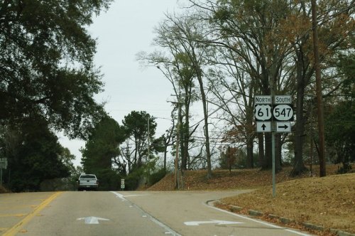 Road sign indicating directions for highways 61 and 547, with a vehicle approaching a fork in the road.
