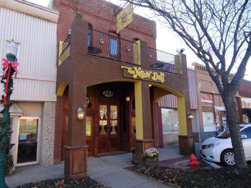 Exterior of The Yellow Deli, featuring a brown facade, yellow accents, and a welcoming entrance with decorative lights.