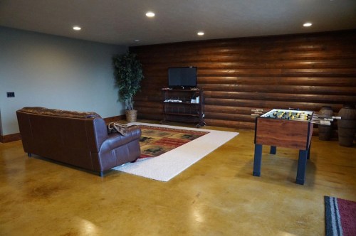 Cozy game room featuring a leather sofa, foosball table, and a wooden accent wall with a TV.