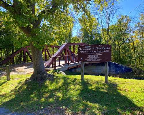 A bridge in the Chesapeake & Ohio Canal National Historical Park, surrounded by trees and a sign indicating the park.