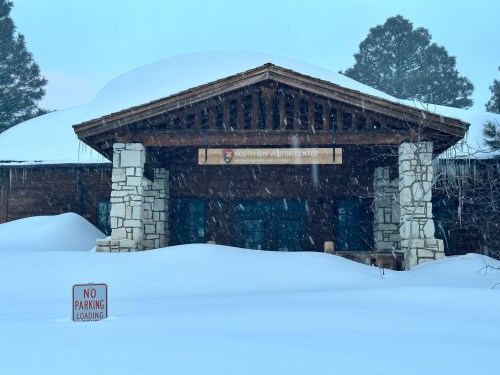Snow-covered entrance of the Northern Rim Visitor Center, with a "No Parking" sign in the foreground.