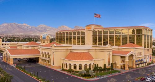 A large hotel and casino building with a flag, set against a backdrop of mountains and a clear blue sky.
