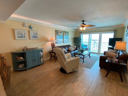 Cozy living room with a view of the ocean, featuring a sofa, armchair, and decorative coastal decor.