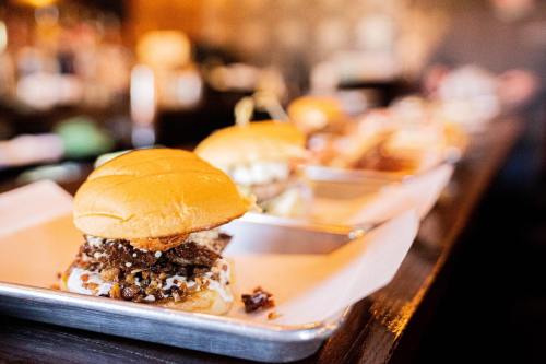 A close-up of a delicious burger on a tray, with other burgers blurred in the background.