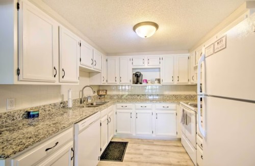 Bright kitchen with white cabinets, granite countertops, and modern appliances, featuring a cozy and inviting atmosphere.