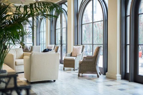 A bright, airy lounge with large windows, comfortable seating, and potted plants, creating a welcoming atmosphere.