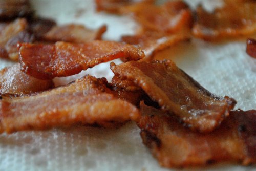 Crispy, golden-brown bacon strips arranged on a paper towel, showcasing their texture and color.