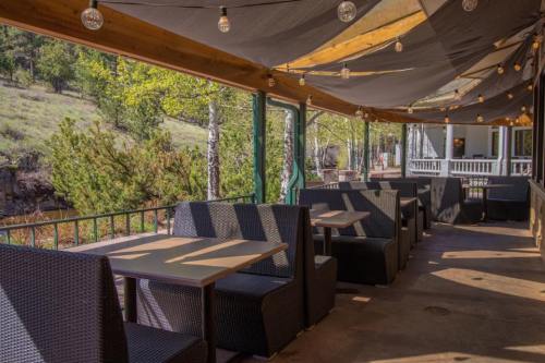 Outdoor dining area with cozy seating, string lights, and a view of greenery in a relaxed atmosphere.